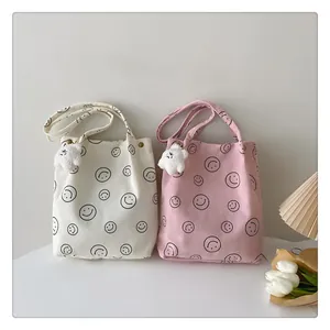 Corduroy tote bags with smiley patterns and plush charms in a cozy room setting