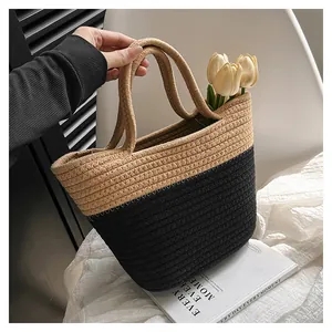 Detail of hand-woven two-tone straw tote bag in beige and black with thick handles