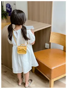 Rear view of a girl wearing a yellow bow mini crossbody bag with a white dress