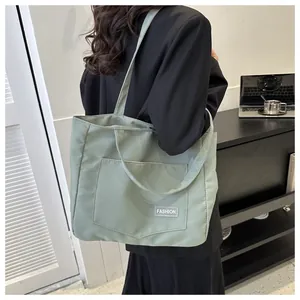 Detailed side view of a large light green canvas tote bag worn by a model