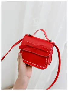 Close-up of a mini red crossbody bag with a leather bow and white stitching details