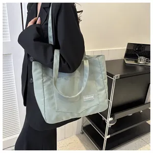 Detail of mint green nylon tote bag featuring spacious front pocket and fashion label