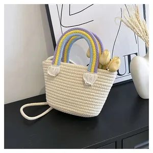 Detail der handgewebten Baumwollseiltasche mit Regenbogengriffen und weißen Quasten