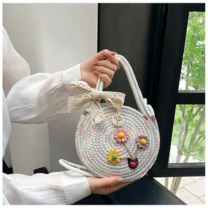 Détail du sac tissé rond avec fleurs 3D et décoration d'un nœud en dentelle beige