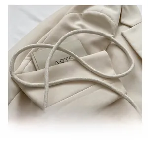Detail of woven beige handbag featuring a thick knotted strap and elegant pearl buckle