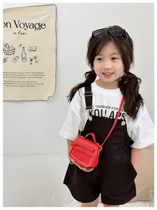 Red kids crossbody bag with bow decoration and white stitching worn by a young model