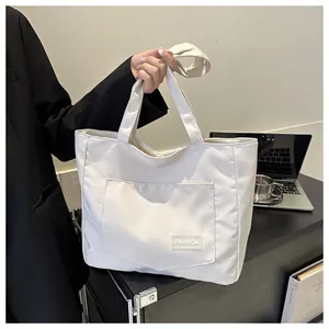 Close-up of beige tote bag with a front pocket and fashion label on a desk