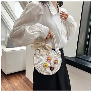 Détail du sac rond en paille avec broderie florale colorée et nœud en dentelle délicat