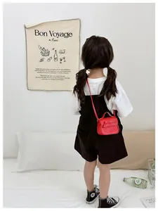 Detail of red children crossbody bag with bowknot and white stitching on PU leather