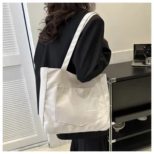 Detailed view of the large front pocket and Fashion tag on a white canvas tote bag