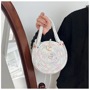Détail du sac d'été rond tissé à la main avec motifs en zigzag colorés et breloque en bois
