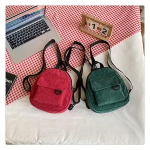 Détail de mini sacs à dos en velours côtelé bordeaux et vert forêt avec sangles réglables