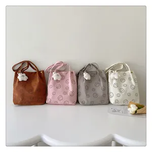 Detail of four colorful corduroy tote bags with smiley patterns and cloud pendants