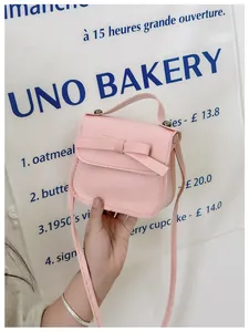 Pink bow mini handbag with shoulder strap held by hand in a cute bakery setting