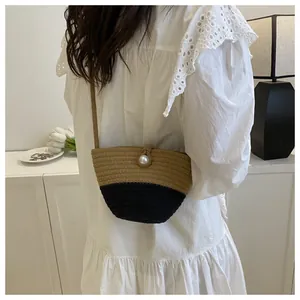 Detail of woven straw bag with black contrast and pearl closure on lace dress