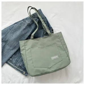 Detail of light bean green canvas tote bag with fashion tag and large front pocket
