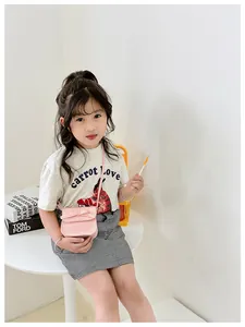 Pink bow crossbody bag for girls paired with a white graphic t-shirt and plaid skirt