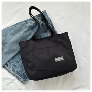 Detailed shot of black nylon tote bag with fashion label on white fabric background