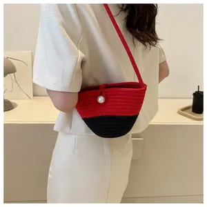 Detail showing handwoven bucket bag in red and black with a large white pearl closure