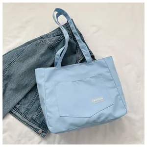 Detail of light blue canvas tote bag featuring an external pocket with FASHION patch