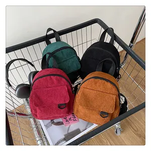Détail de mini sacs à dos en velours côtelé en quatre couleurs dans un chariot en métal