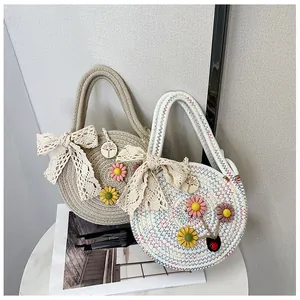 Détail du sac de plage tressé avec nœuds en dentelle, fleurs et pendentif en bois