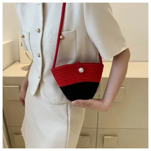 Detail of red and black woven crossbody bag with a decorative large white pearl button