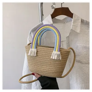 Detail der gewebten Strohtasche mit Regenbogen-Baumwollgriffen und cremeweißen Quasten