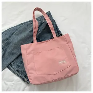 Detail of pink canvas tote bag with fashion label and front pocket on white fabric
