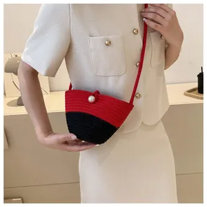 Detail of hand-woven mini bucket bag with red and black stitching and pearl button