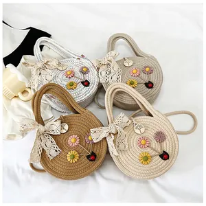 Détail de sacs ronds en paille tressée avec fleurs 3D et nœuds en ruban de dentelle