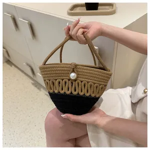 Detail of hand-woven straw bag featuring bicolor design and decorative pearl buckle