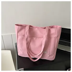 Detailed macro view of a pink nylon tote bag featuring a Fashion label on the front pocket