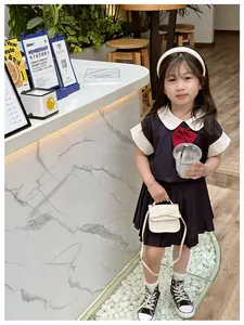 Detail of girls' navy school uniform dress with red bow and white crossbody purse