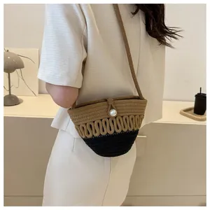 Close-up of woven crossbody bag with bicolor pattern and large pearl clasp detail