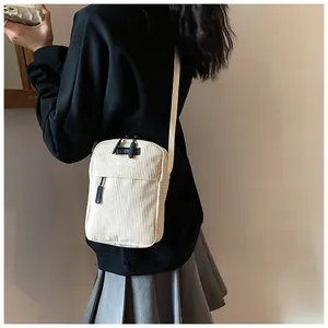 Detail of off-white corduroy crossbody bag with double zippers and brand label