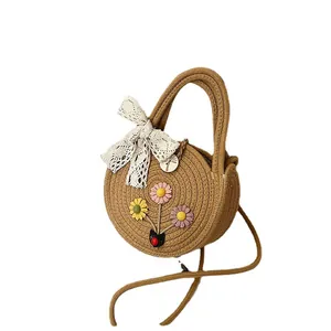 Sac bandoulière rond en paille fait main avec nœud en dentelle blanche et fleurs colorées