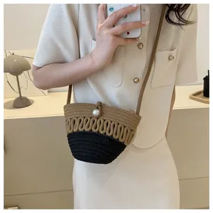 Detail of woven bucket bag featuring two-tone design and elegant pearl button closure