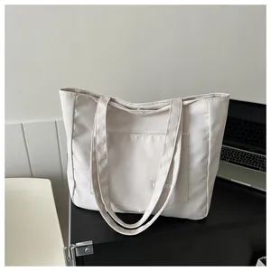 Close-up of minimalist cream canvas tote bag featuring front pocket and fashion label