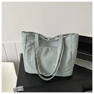 Close-up of light green nylon canvas tote bag with fashion label on office desk