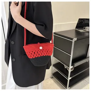 Detail of red and black woven crossbody bag featuring a white pearl buckle closure