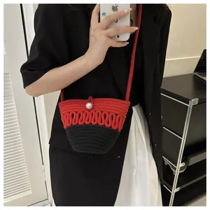 Mirror selfie showing the red and black woven bucket bag with a large pearl closure