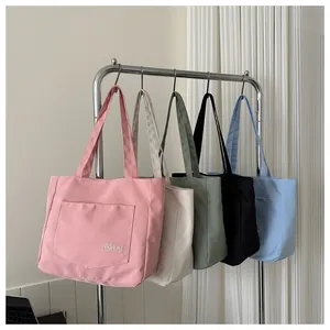 Detail showing five colors of canvas tote bags with front pockets and fashion tags