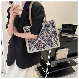 Ethnic style woven tote bag shown on shoulder with colorful geometric patterns