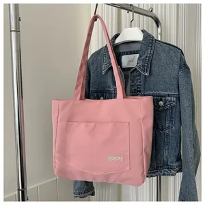 Close-up of pink canvas tote bag with fashion label on front pocket for daily use