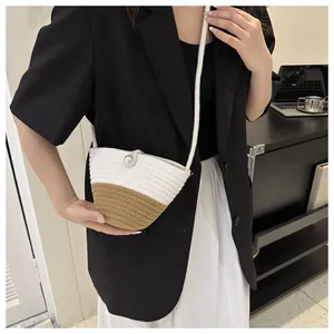 Detail view of woven straw crossbody bag featuring a pearl button and dual-tone stitching