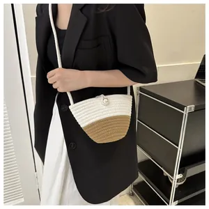Detail of woven shell-shaped crossbody bag with pearl button closure on model