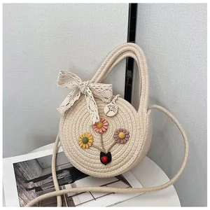 Beige round woven straw bag with colorful floral appliques and lace bow detail