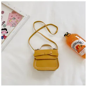 Detail view of ginger yellow kid's crossbody bag with bow decoration and white stitching
