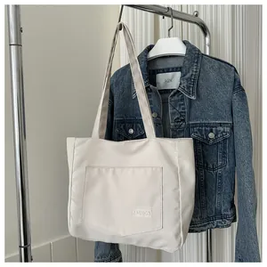 Detail of off-white tote bag featuring a functional front pocket with FASHION logo tag